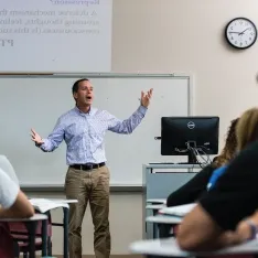 A man teaching in a classroom filled with attentive students.